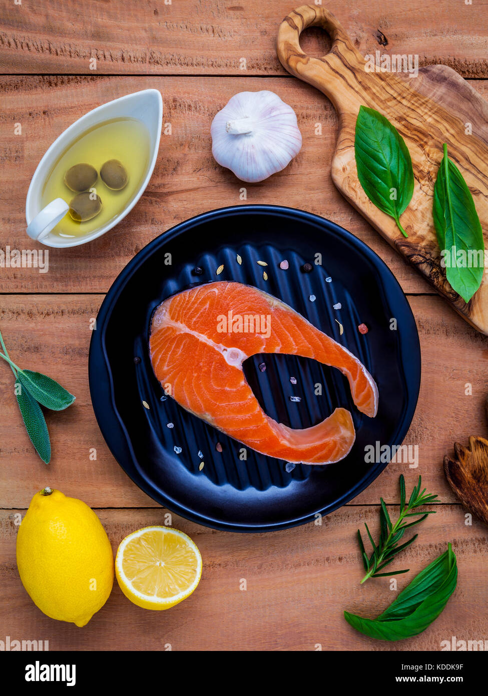 Rohes Lachsfilet in die schwarze Platte mit Zutaten Olivenöl, Himalaya Salz, Kräuter, Basilikum, Fenchel, Salbei, Rosmarin, Knoblauch, Pfeffer und Lem Stockfoto