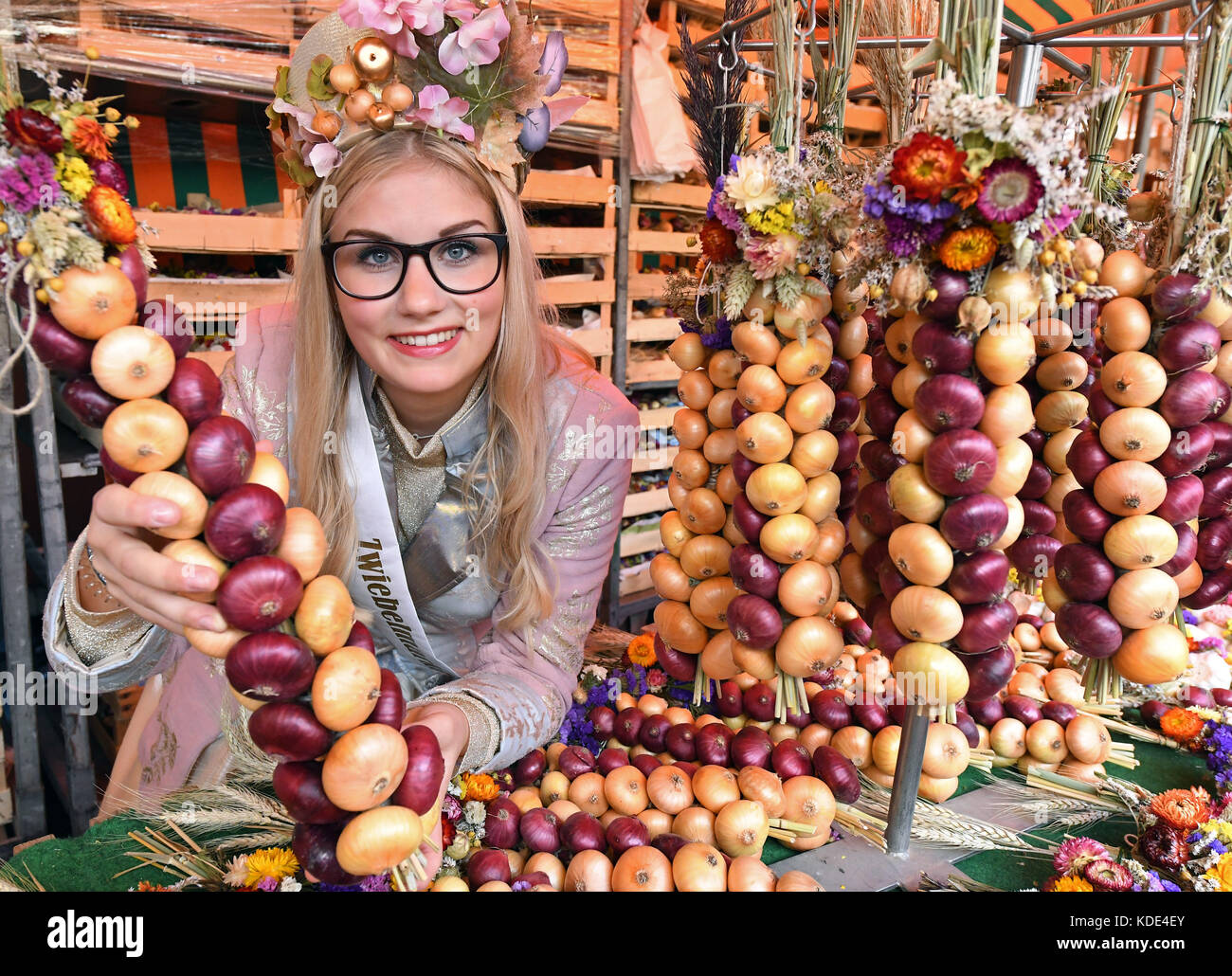 Weimar, Deutschland. 13. Oktober 2017. Die Zwiebelmarktkönigin, die 19-jährige Gina-Marie Hildebrandt-Kanhold, präsentiert auf dem Weimarer Zwiebelmarkt 364. die traditionellen geflochtenen Zwiebelbrötchen. Weimarer Zwiebelmarkt) in Weimar, Deutschland, 13. Oktober 2017. Bis zum 15. Oktober lockt Thüringens berühmtestes Volksfest rund 300,000 Besucher an. Rund 500 Stände bieten die beliebten rot-weißen zwiebelgeflochtenen Bunchs, warme Zwiebeltarte, Thüringer Bratwurst, Getränke und Kunsthandwerk. Quelle: Martin Schutt/dpa-Zentralbild/dpa/Alamy Live News Stockfoto