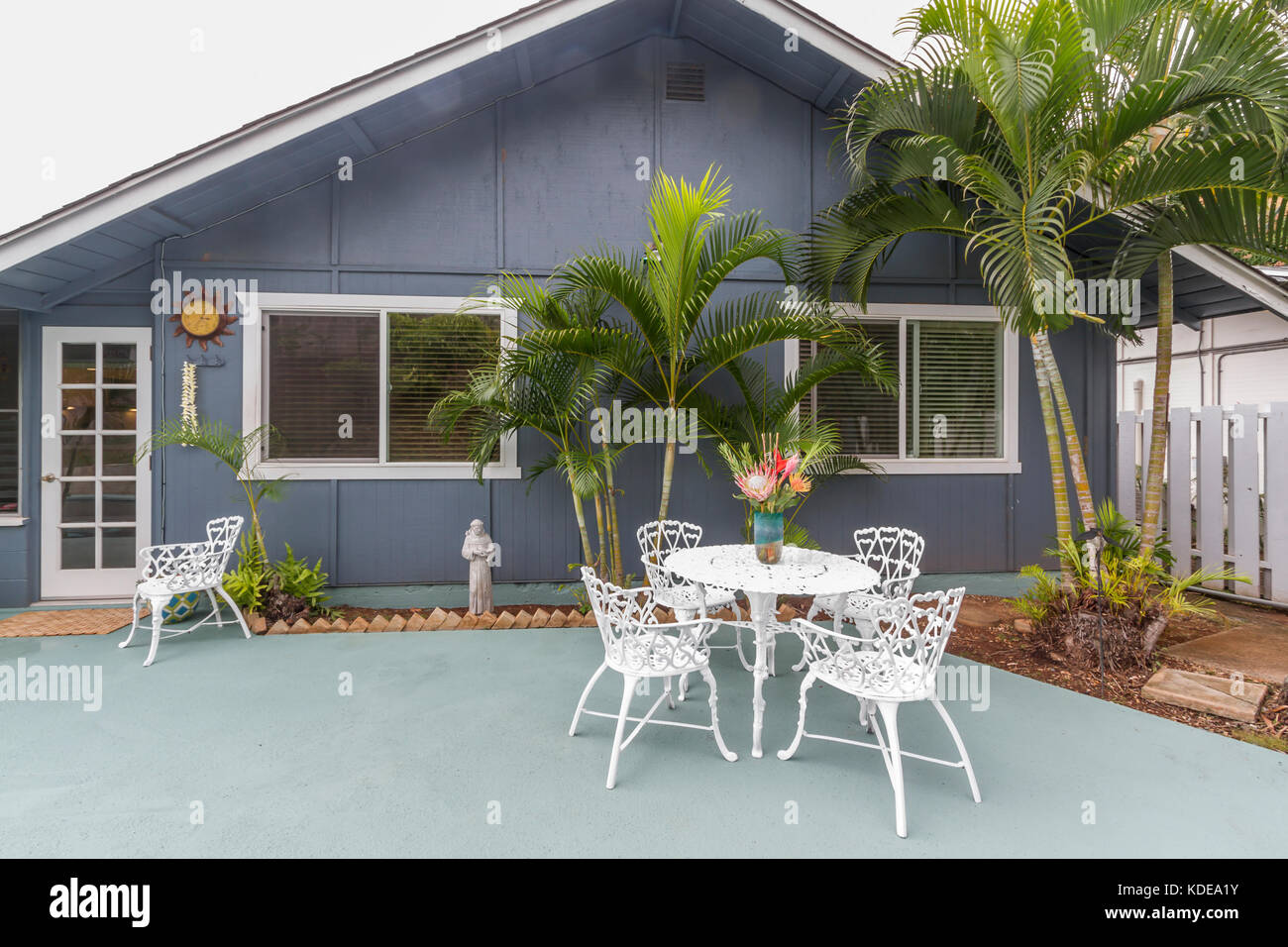 Home Exterieur, Outdoor Living, blau Terrasse Sitzecke mit weißen schmiedeeisernen Tischen, Stühlen und tropischer Landschaft. Stockfoto