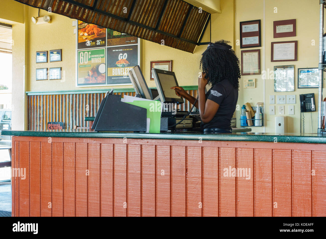 Ein Mitarbeiter nimmt eine Bestellung am Telefon, trägt sie in einen Computer am Flügel, ein Chicken Wing food Restaurant und eine Sportbar. Oklahoma City, OK, USA Stockfoto