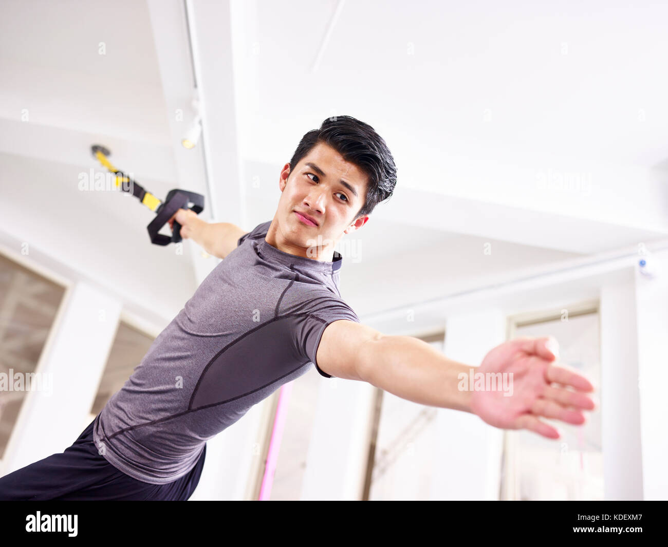 Junge asiatischer Mann das Trainieren im Fitnessstudio mit Fitness-Trägern. Stockfoto