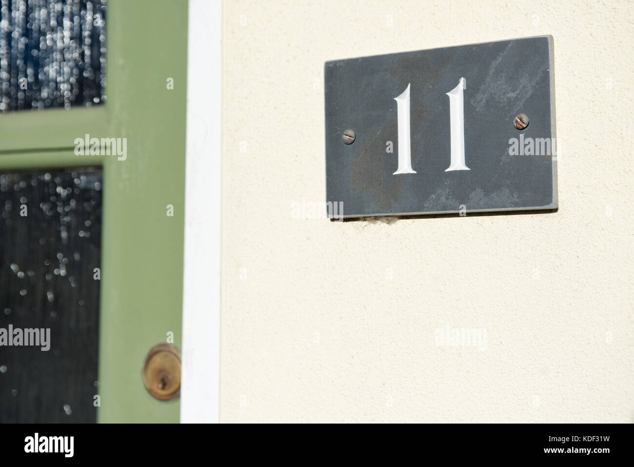 Ein grauer Schiefer Tafel zeigt eine weiße Zahl 11, die an der Außenseite eines Hauses angebracht. Identifizieren von seiner Adresse. Stockfoto