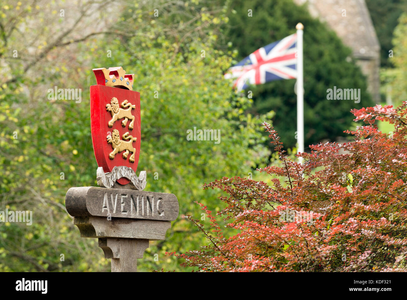 Das Zeichen in der Mitte des historischen Cotswold Dorf avening, glocestershire, uk. Zwischen herbstlichen Bäume mit hinter einer Union Flag flattern. Stockfoto