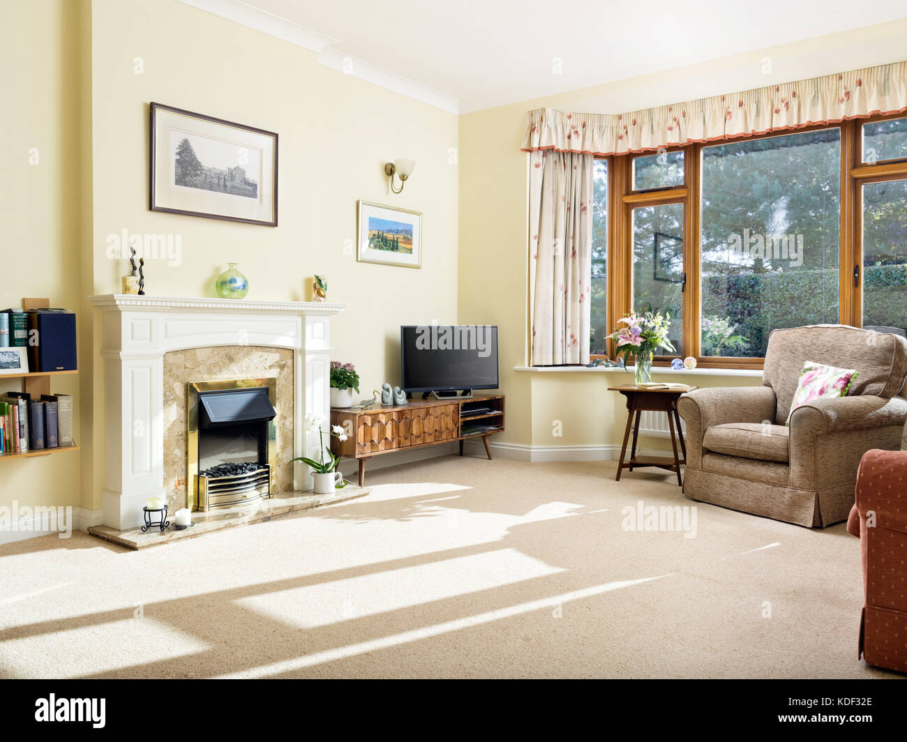 Eine datierte, möblierten, sonnigen Wohnzimmer mit Kamin in einem Haus im typischen Stil von vielen Wohnungen von älteren Menschen besetzten eingerichtet Stockfoto