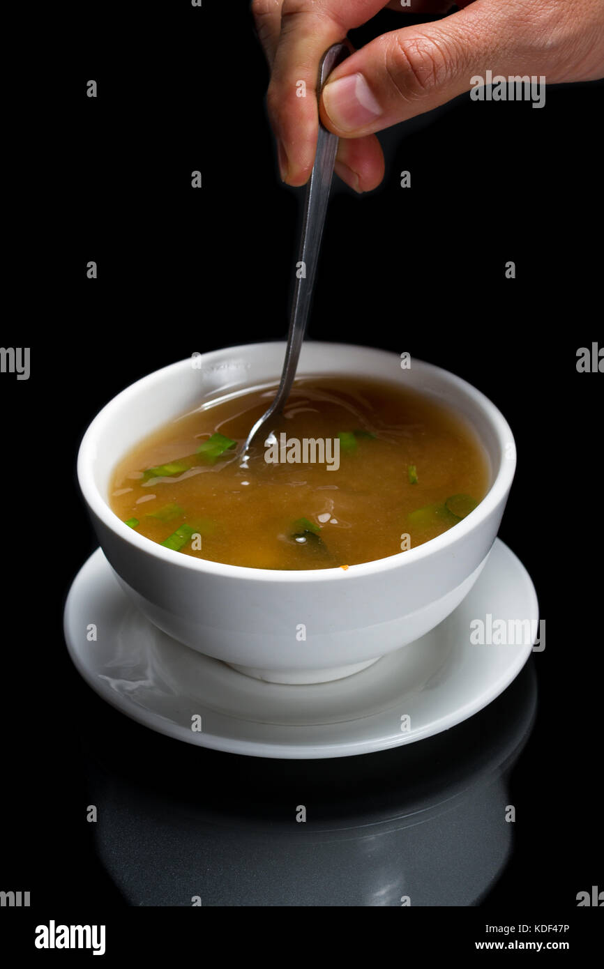 Heiße Tasse Miso Suppe mit Frühlingszwiebeln und Seetang mit einem Löffel gespeichert werden. Stockfoto