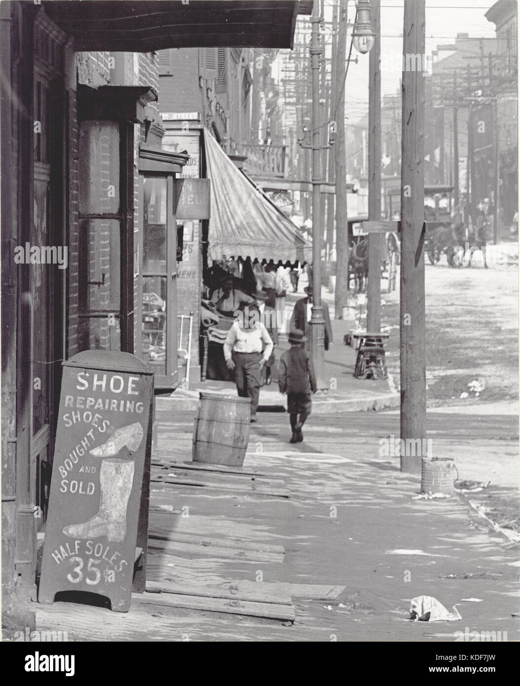 Bürgersteig Szene auf einem nicht identifizierten Straße. Schuhreparatur shop Schild auf der linken Hälfte Sohlen (35 Cent) Stockfoto