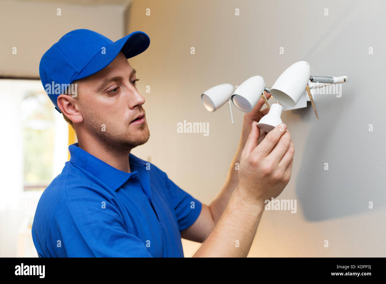 Die elektrische Instandhaltung - Elektriker ändern Glühbirne in Wandleuchte Stockfoto