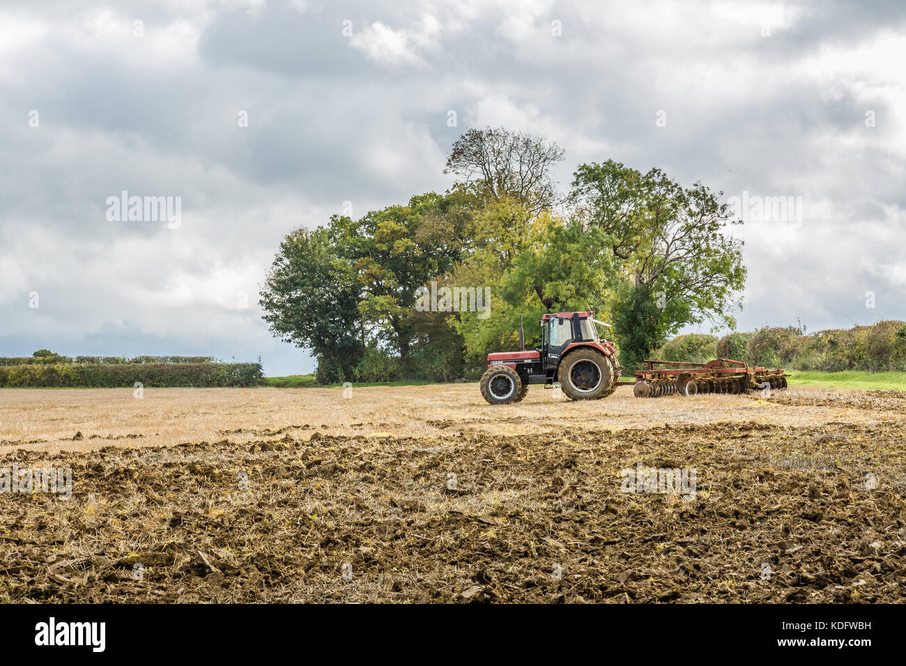 Ein Roter Traktor in ein Feld angezeigt, in herbstlichen Farben und Ackerland Stockfoto