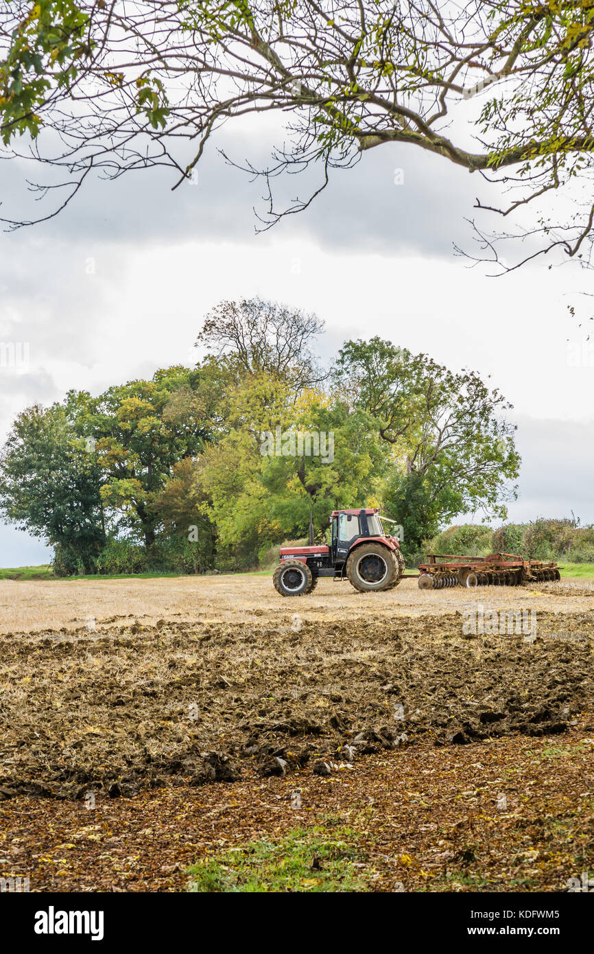Ein Roter Traktor in ein Feld angezeigt, in herbstlichen Farben und Ackerland Stockfoto