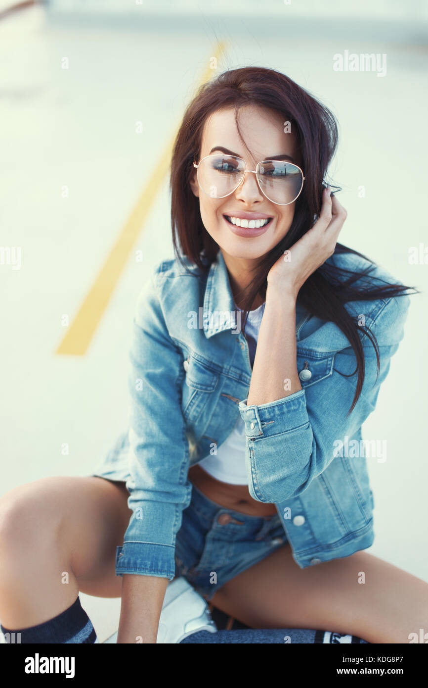 Gerne stilvolle Smart sorglos brünette Frau in Jeans lächelnd Outdoor, urban fashion Stockfoto