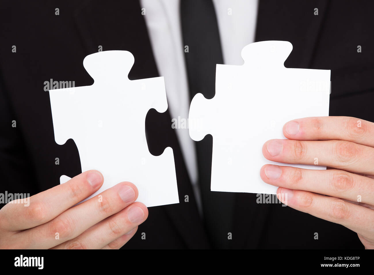 Nahaufnahme eines Geschäftsmannes Lösung Puzzle im Büro Stockfoto