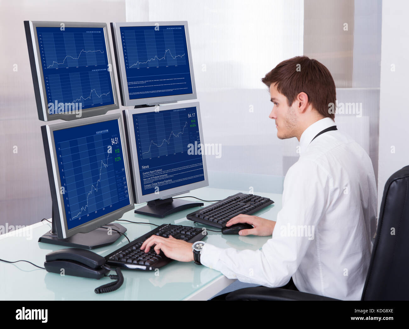 Porträt der jungen Börsenmakler mit Computer am Schreibtisch Stockfoto