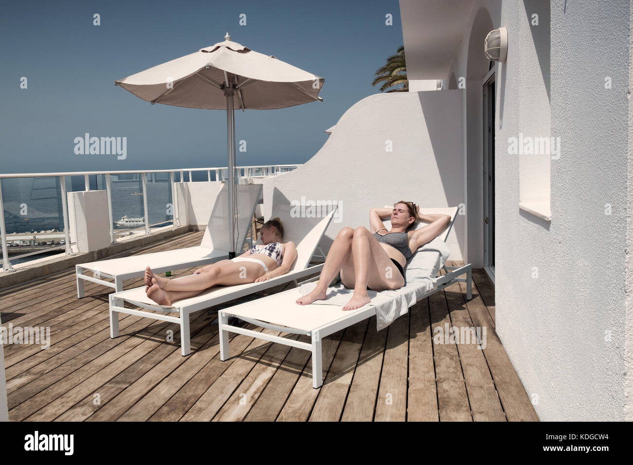 Zwei Frauen Sonnenbaden im Sommerurlaub auf den Sonnenliegen liegen auf einem privaten Balkon. instagram Effekt angewendet werden Stockfoto