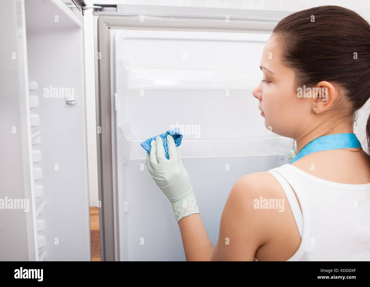 Rückansicht einer jungen Frau, die Reinigung Kühlschrank Stockfoto