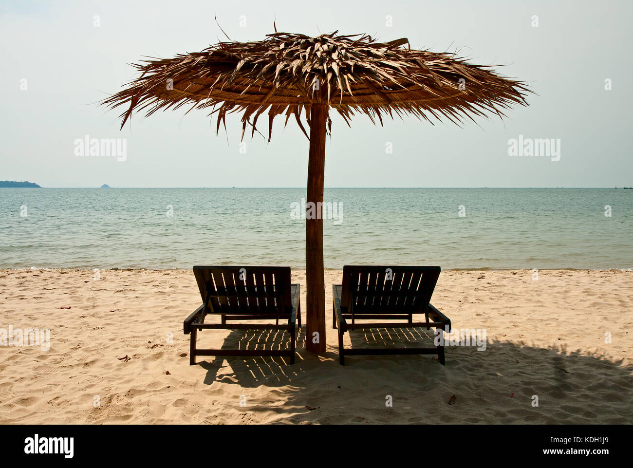 Sonnenliegen unter einem Sonnenschirm an einem tropischen Strand Stockfoto
