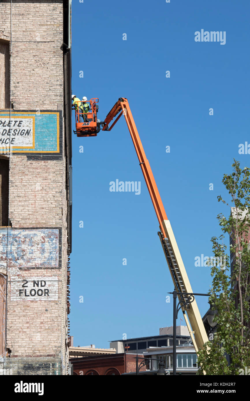 Grand Rapids, Michigan - zwei Männer auf einem Cherry Picker arbeiten an der Seite eines alten Innenstadt Gebäude. Stockfoto