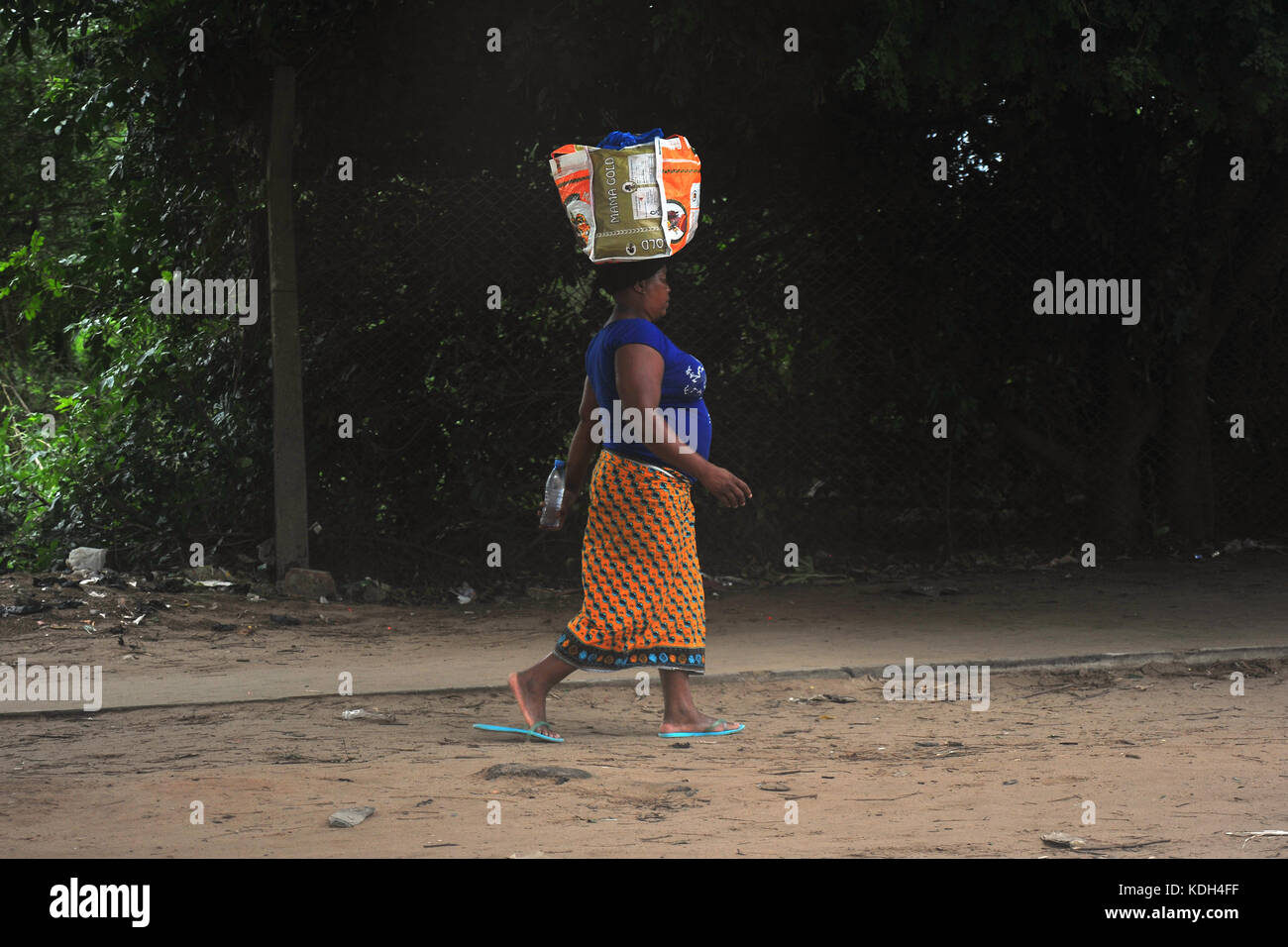 Eine Frau, die zu Fuß mit einem Paket auf ihrem Kopf in Mosambik. Stockfoto