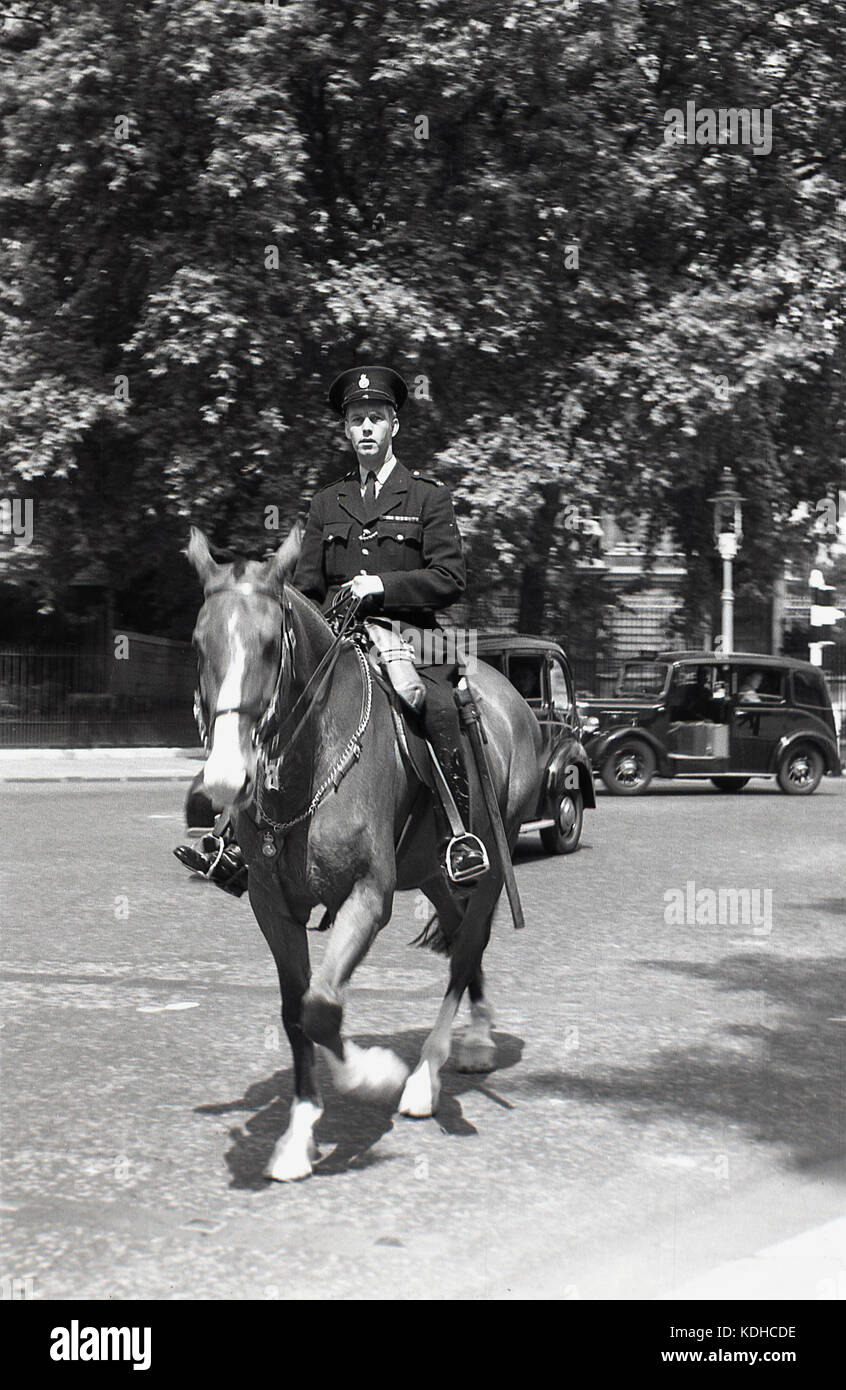 1950er, London, Westminster, historisches Bild eines berittenen britischen Polizisten zu Pferd, mit einem Londoner Taxi der Zeit im Hintergrund. Beachten Sie den Freiluftbereich im Taxi neben dem Fahrer, ein Platz, um Gepäck unterzubringen. Stockfoto