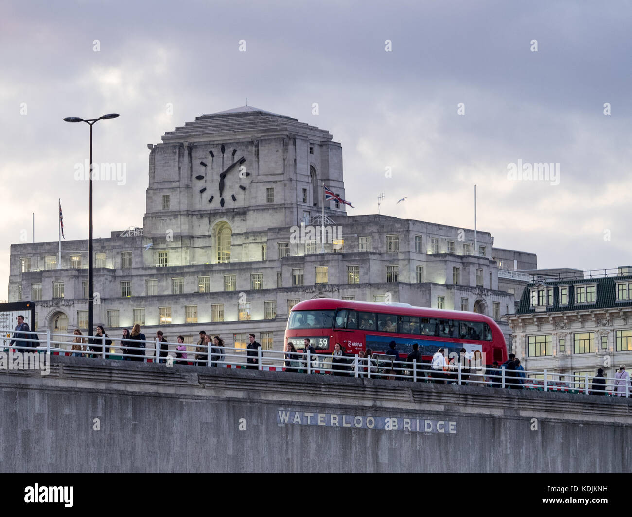London Bus und Pendler kreuz Waterloo Bridge vor der Shell Mex House in London in der Dämmerung Stockfoto