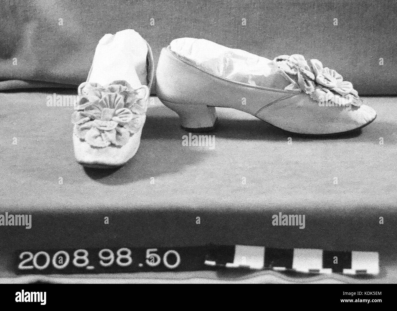 Dies bezieht sich auf ein Paar Damenschuhe aus weißem Kinderleder mit dekorativen weißen Blüten auf der Zehenspitze. Er unterstreicht Mode und Handwerkskunst im Schuhdesign. Stockfoto