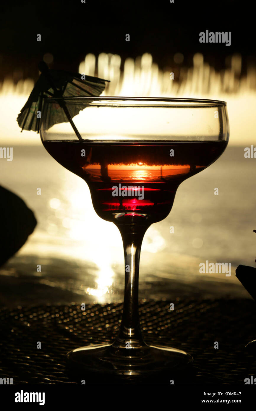 Cocktail Glas mit im Hintergrund, um den Sonnenuntergang in das Glas reflektiert. tropische Insel. Stockfoto