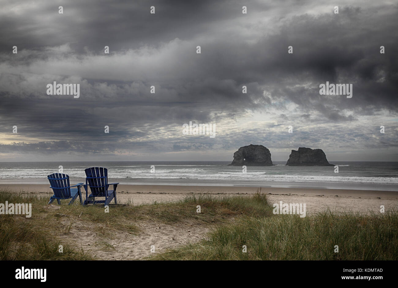Eine romantische oceanscape mit Moody sky einschließlich zwei Adirondack Stühlen mit Blick auf das Meer stack Felsformationen in Rockaway Beach, Oregon. Stockfoto