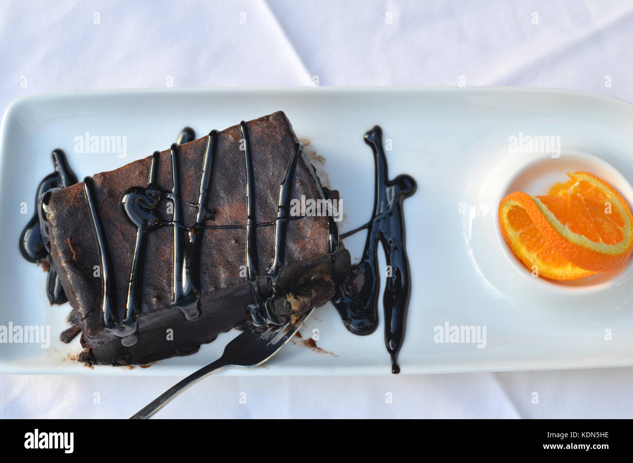 Schokolade Kuchen mit einer Scheibe Orange - auf weißem Porzellan Platte Stockfoto