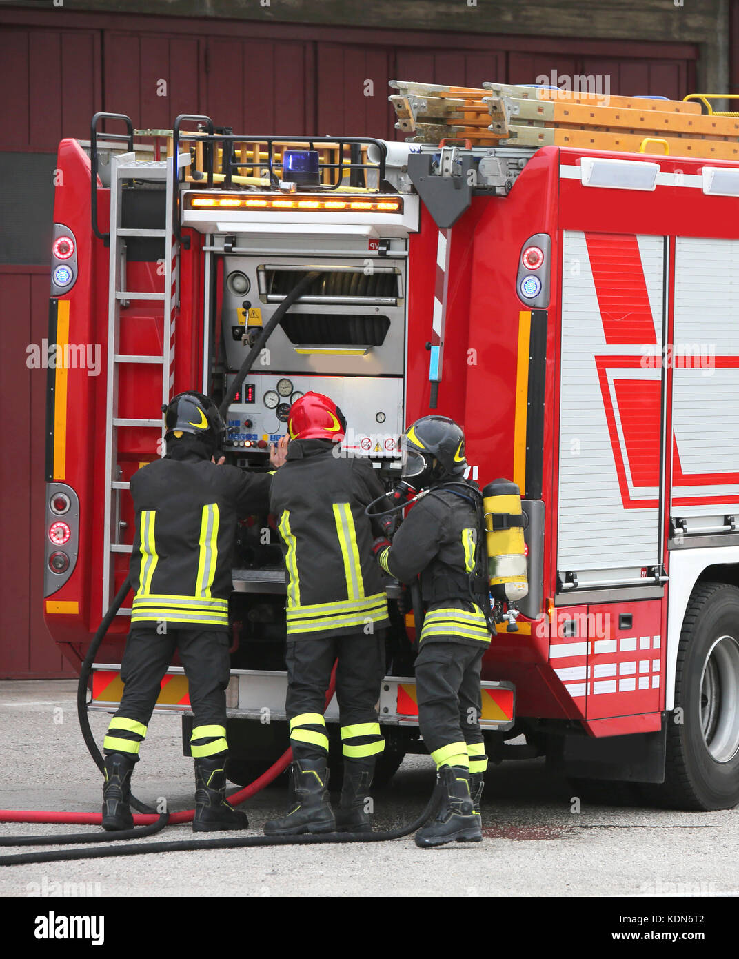 Drei Feuerwehrmänner und Tankwagen im Brandfall Prävention Übung Stockfoto