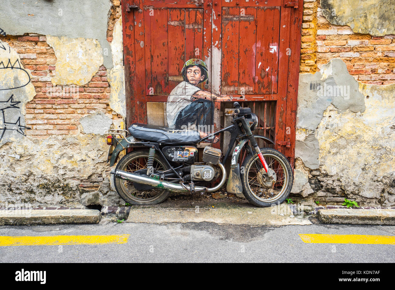 Penang, Malaysia – 21. Mai 2016: Das Gemälde eines Jungen, der auf einem alten Motorrad sitzt, in George Town, Penang, Malaysia. Stockfoto