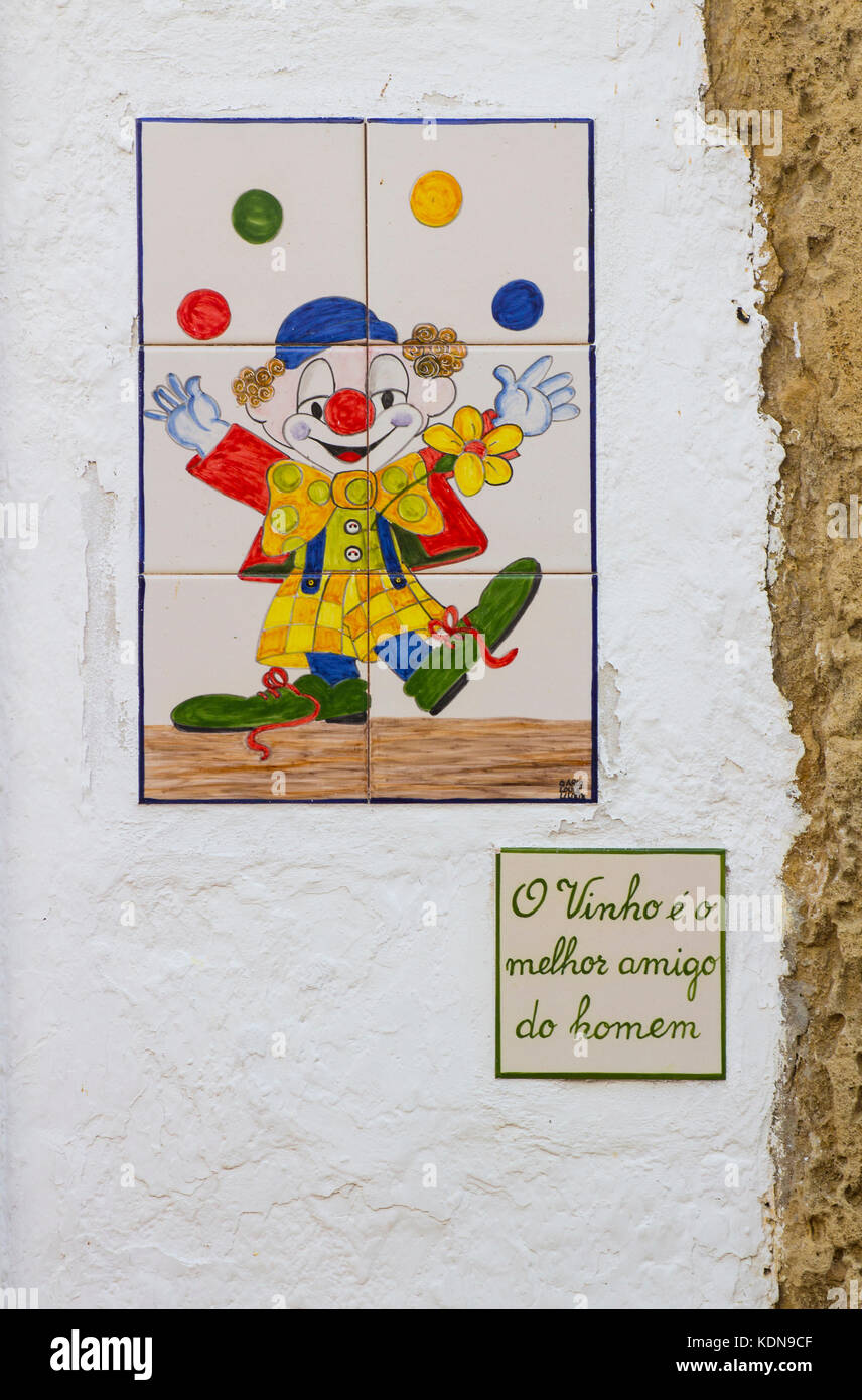 Eine geflieste Tafel eines jonglierenden Zirkusclowns mit einer schriftlichen Beschriftung in portugiesischer Sprache, die besagt: „Wein ist der beste Freund des Menschen“ Stockfoto