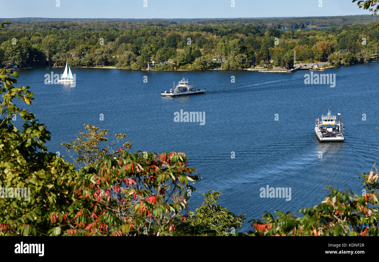 Kostenloses Glenora-Auto Fähren nach Adolphustown auf blauem Adolphus-Reach mit weißem Segelboot auf der Bay of Quinte, Prince Edward County Ontario im Herbst Stockfoto