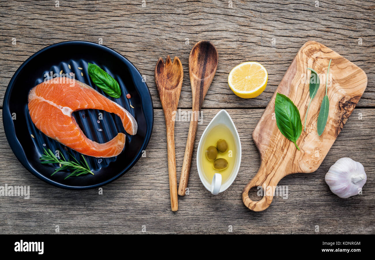 Rohes Lachsfilet in die schwarze Platte mit Zutaten Olivenöl, Himalaya Salz, Kräuter, Basilikum, Fenchel, Salbei, Rosmarin, Knoblauch, Pfeffer und Lem Stockfoto