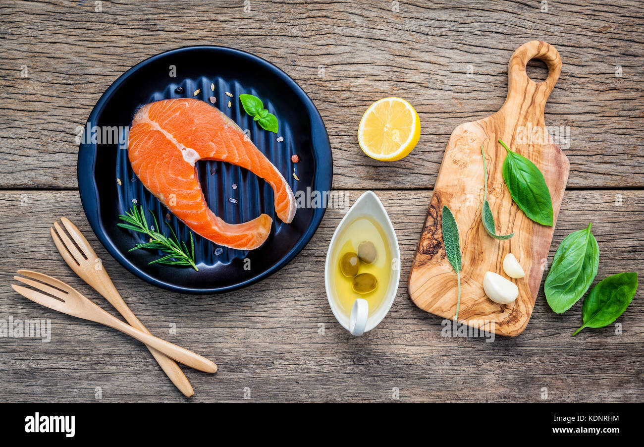 Rohes Lachsfilet in die schwarze Platte mit Zutaten Olivenöl, Himalaya Salz, Kräuter, Basilikum, Fenchel, Salbei, Rosmarin, Knoblauch, Pfeffer und Lem Stockfoto