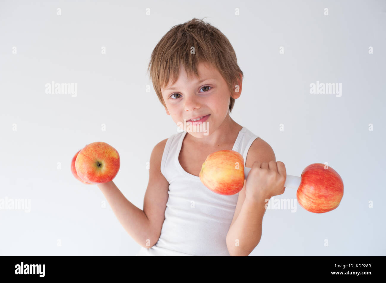 Schönen Lächeln kleiner Junge hält zwei Gewichte von Frische rote gelbe Äpfel gemacht Stockfoto