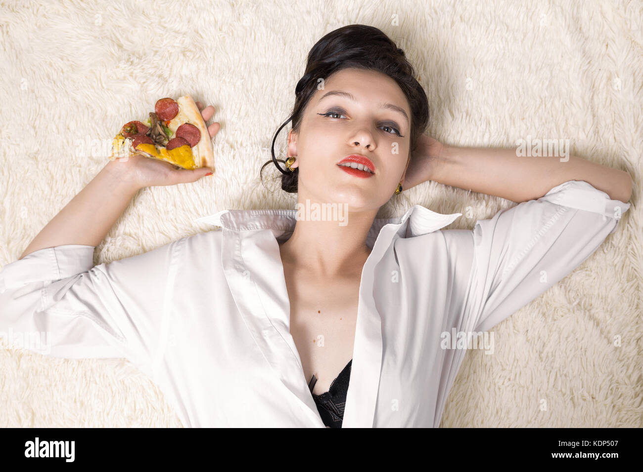 Schöne überessen Geschäftsfrau liegend mit Pizza Stücke Stockfoto