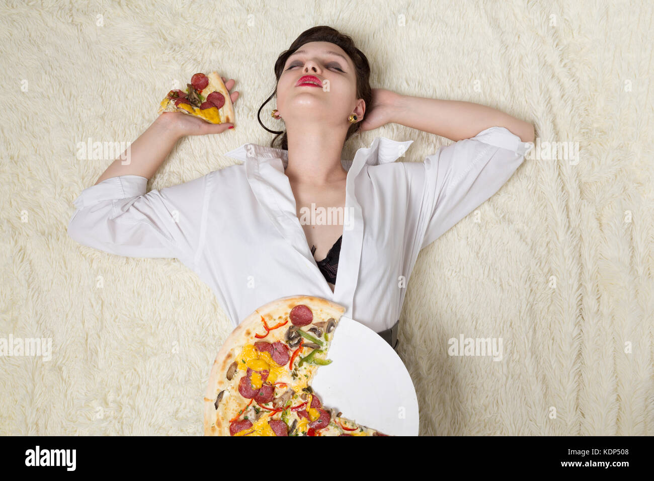 Schöne überessen Geschäftsfrau liegend mit Pizza Stücke Stockfoto