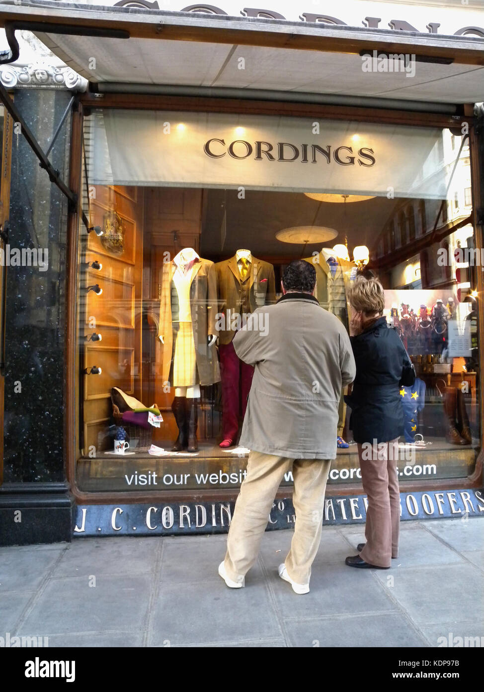 2000, tagsüber, Piccadilly, London, ein Mann und eine Frau stehen und schauen Sie sich die klassische britische Kleidung auf Anzeige an Cordings von Piccadilly, ein Speicher mit einer berühmten Erbe und Kundenstamm und im Geschäft als Herren Ausstatter seit 1839. Zusammenarbeit von British Rock Legende Eric Clapton. Stockfoto