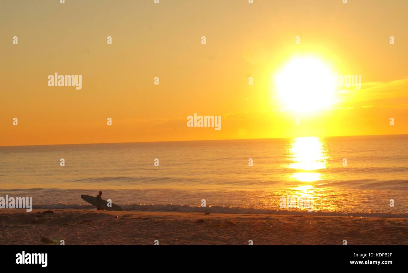Eine einladende Sonnenaufgang auf der New Jersey Shore in Ocean Beach als Surfer wartet auf die perfekte Welle. Stockfoto