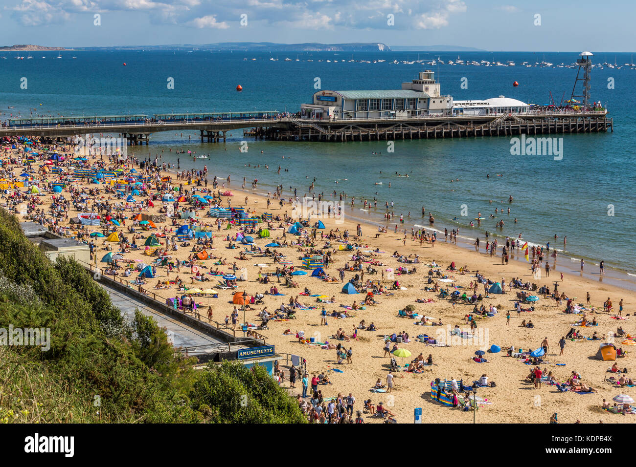 Bournemouth Pier und Strand voller Sonnenanbeter an einem sonnigen Tag im August. Die Nadeln auf der Insel Wight können auch gesehen werden, Bournemouth England Großbritannien Stockfoto