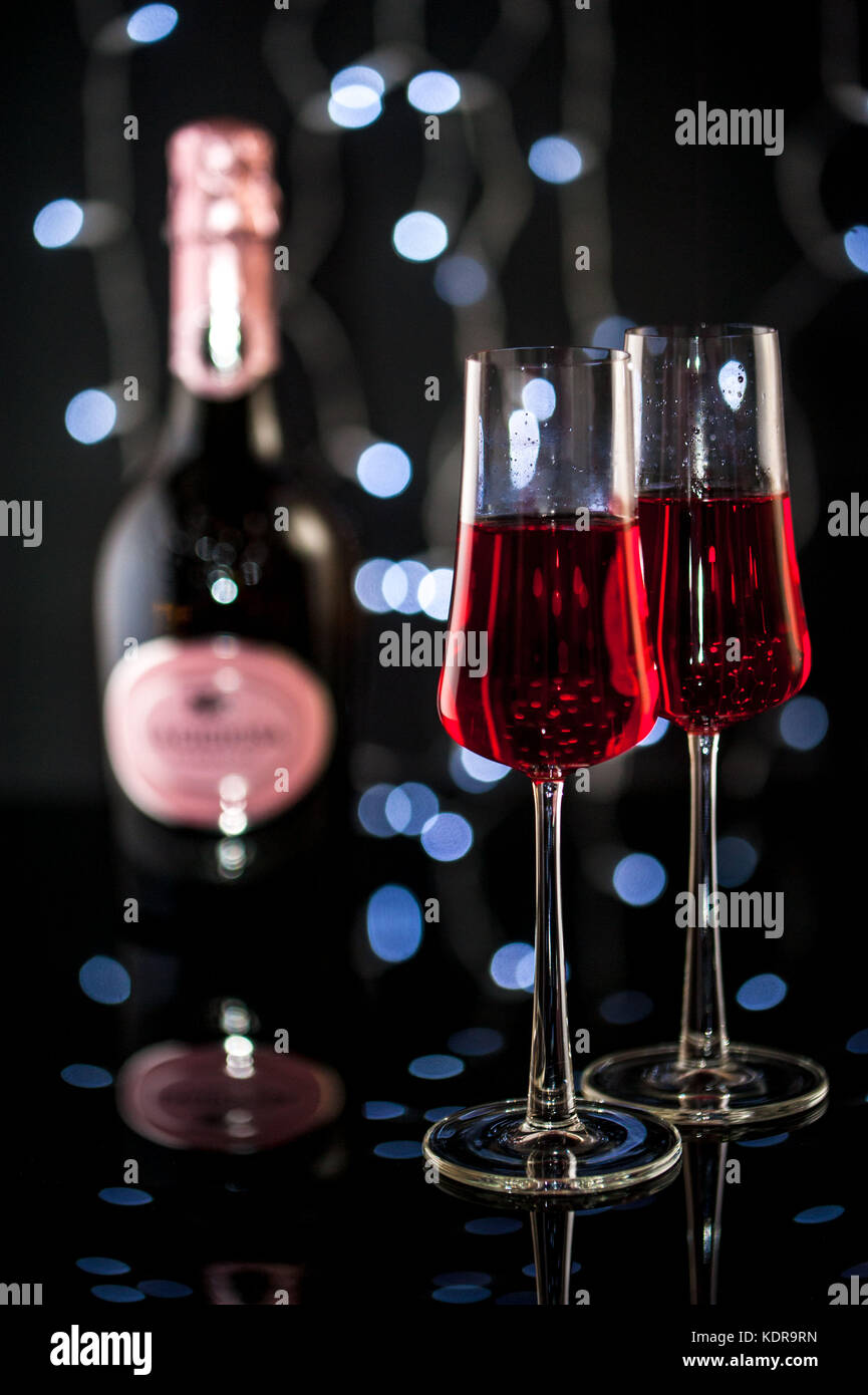 Zwei Gläser mit rosa Champagner, Flasche Champagner und Weihnachtsbeleuchtung auf einem Hintergrund Stockfoto