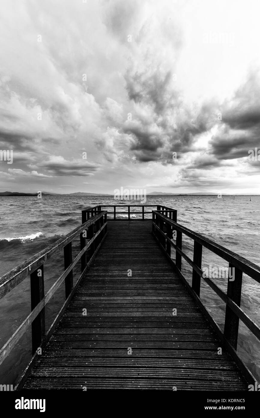 First Person Ansicht einer Pier auf einem See auf einem Stimmungsvollen Tag, mit dunklen Wasser und bedeckt, stürmischen Himmel Stockfoto