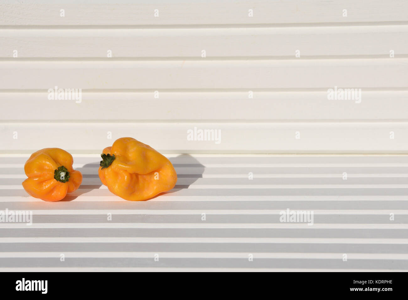 Essen Fotografie Bild von gelb orange scotch bonnet Chilis in der Sonne mit weißem Holz natürliche Hintergrund und an der Südküste genommen England Großbritannien Stockfoto