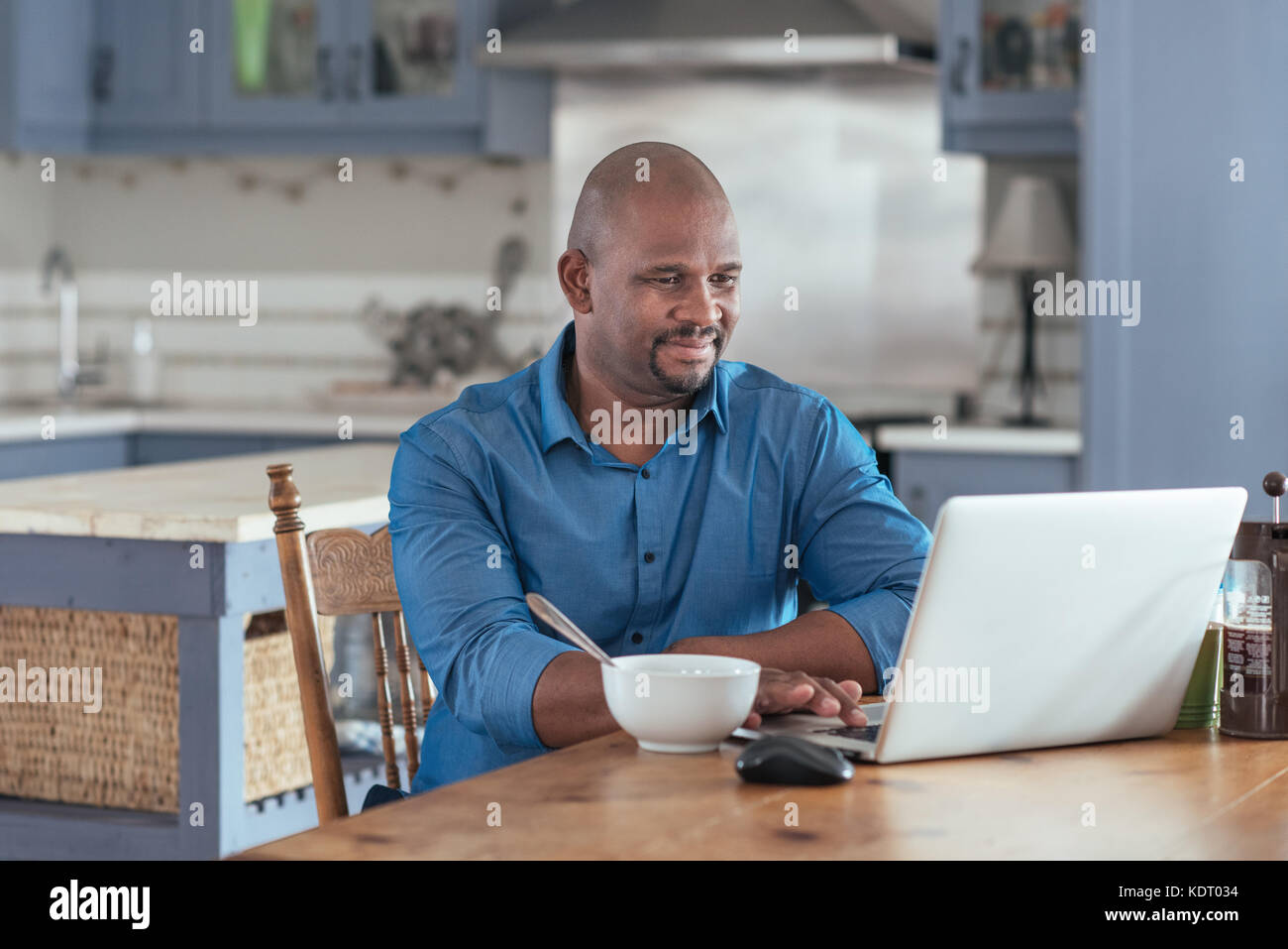 Reifen afrikanischer Mann online Surfen mit dem Laptop über das Frühstück Stockfoto