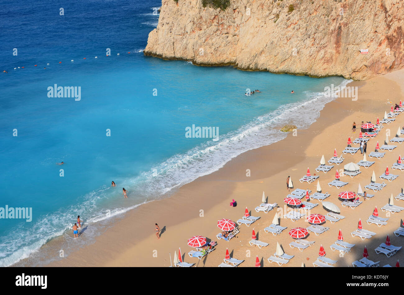 Mutter gibt ein Kind eine helfende Hand Spaziergang durch Wellen am Strand zu verlassen. Familie Liebe und Unterstützung in lustigen Tag auf Sunny Beach - Türkei Stockfoto