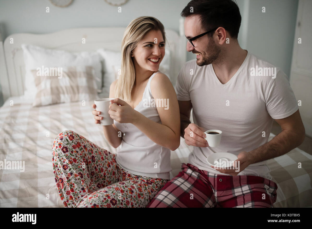 Bild von jungen glückliches Paar sitzt auf dem Bett Stockfoto