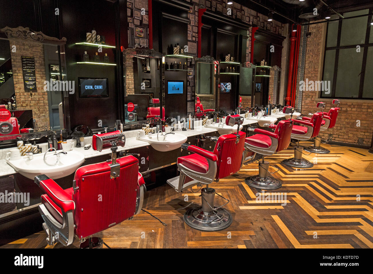 Innerhalb eines modernen Friseure shop in London, England. Zeigt eine Mischung aus Vintage suchen Möbel und digitale Fernsehgeräte, mit gemusterten Holzboden. Stockfoto