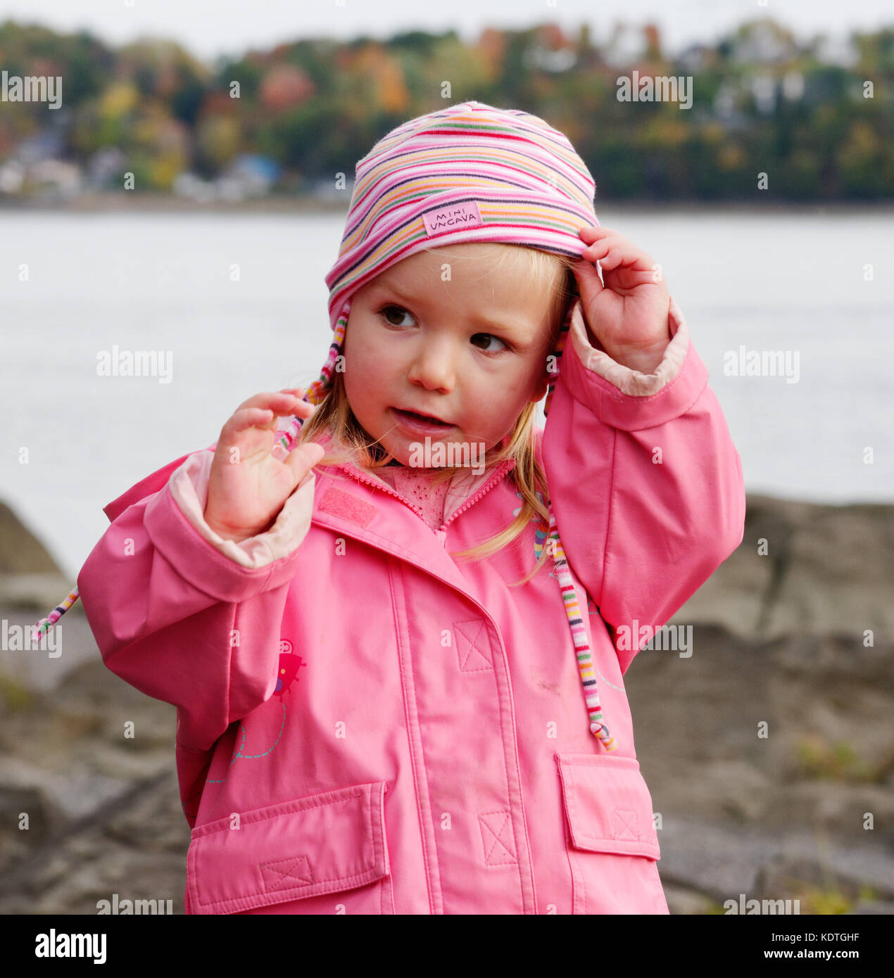 Ein kleines Mädchen (3 Jahre alt) trägt einen rosa Regenmantel und Hut Stockfoto