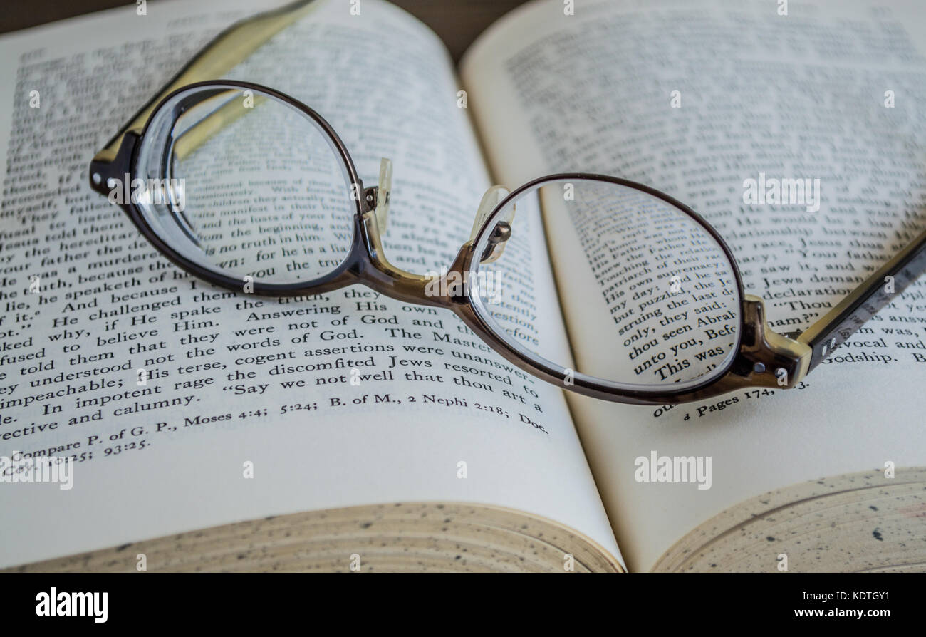 Kopfüber Brille auf einem offenen religiösen Buch ruht Stockfoto