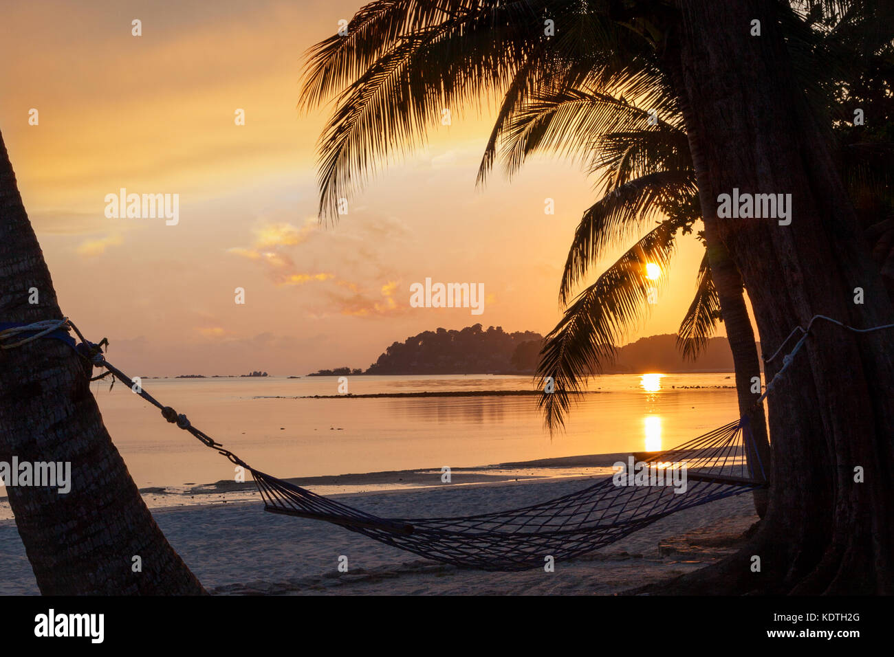 Schönen goldenen Sonnenaufgang über den Sandstrand auf der Insel Bintan in Indonesien mit Silhouette der Hängematte und Kokospalmen mit kopieren. Stockfoto