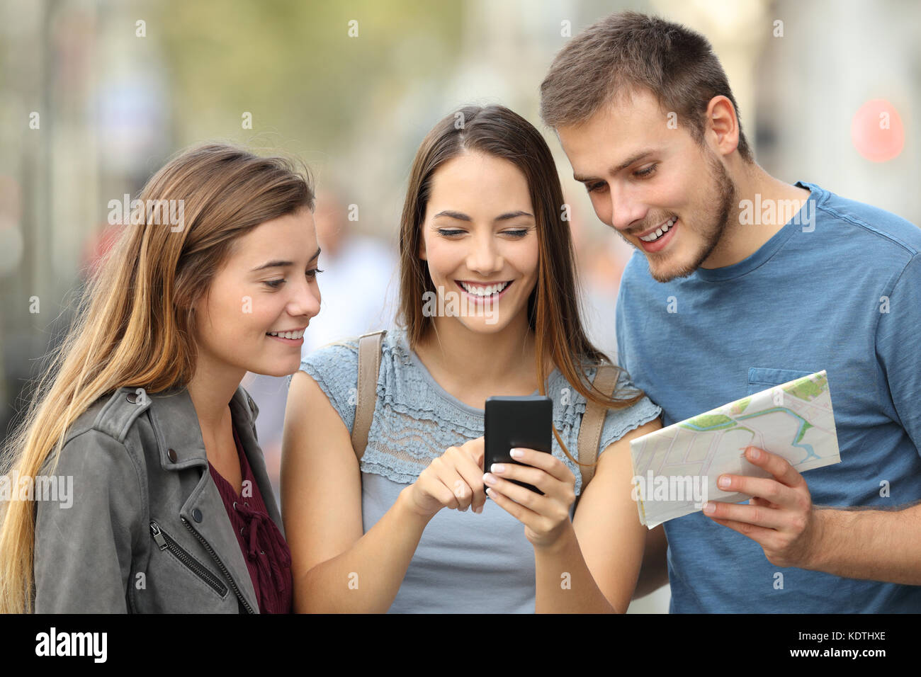 Drei Touristen die Kontrolle über eine Karte und ein smart phone auf der Straße Stockfoto